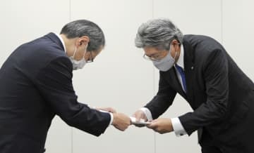 総務省総合通信基盤局の竹村晃一局長（左）から行政指導の文書を受け取るNTT西日本の森林正彰社長＝30日午前、総務省