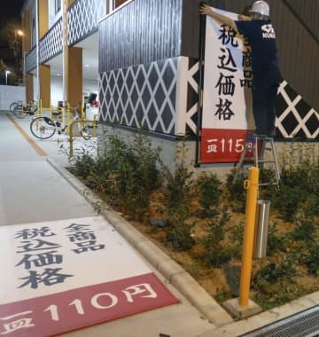 価格が表示された垂れ幕を交換するくら寿司朝潮橋店の従業員＝9月30日夜、大阪市港区