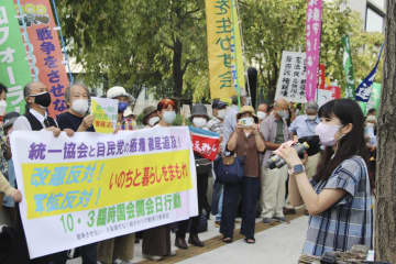 国会議事堂前で横断幕やプラカードを持ち、抗議活動する参加者＝3日午後、東京・永田町