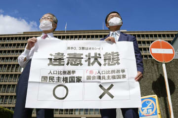 参院選の「1票の格差」訴訟の判決を受け、大阪高裁前で「違憲状態」と書かれた紙を掲げる原告側の升永英俊弁護士（左）ら＝14日午後