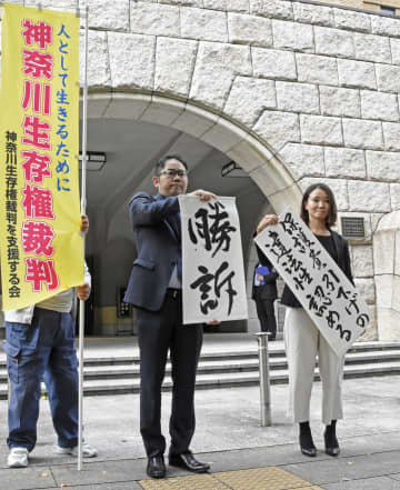 生活保護費減額処分の取り消しなどを求めた訴訟の判決後、「勝訴」と書かれた紙を掲げる弁護士ら＝19日午前、横浜地裁前