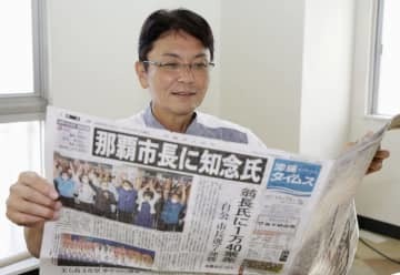 那覇市長選から一夜明け、初当選を報じる新聞を手にする知念覚氏＝24日午前、那覇市