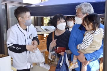 1日限定で復活した福島県大熊町のキウイ直売所で、訪れた人と話す関本元樹さん（左端）＝3日午後