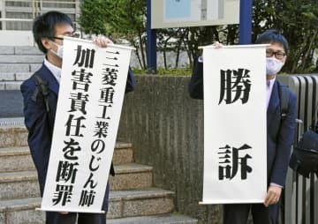 判決後に「勝訴」などと書かれた垂れ幕を掲げる原告側弁護士＝7日午前、長崎地裁前