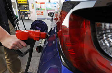 ガソリンスタンドで給油する人＝3月、東京都内
