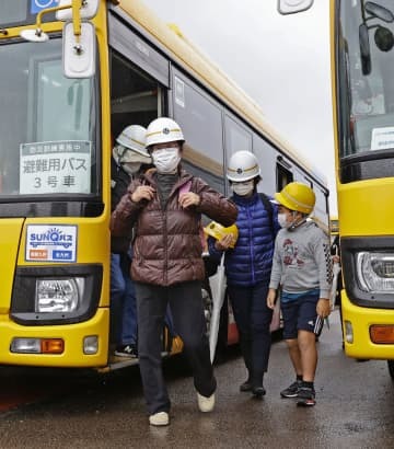 桜島の大規模噴火を想定した訓練で、避難用のバスから降りる参加者＝19日午前、鹿児島市