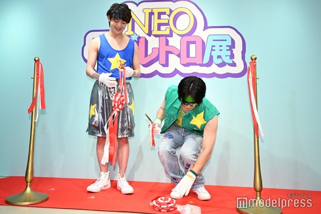 慣れないテープカットでなかなか切れず切れた瞬間装飾を落としてしまった久間一平（右）、それを見守る大地守（左）／Chi☆Q（C）モデルプレス
