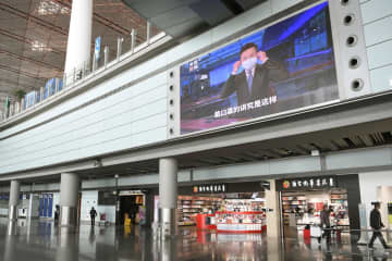 閑散とする北京首都国際空港の到着ロビー。大型モニターにはマスク着用を呼び掛ける映像が流れていた＝12日（共同）