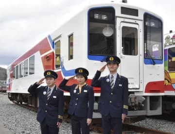 辞令交付後に、車両の前で記念撮影に応じる三陸鉄道の新入社員＝1日午前、岩手県宮古市